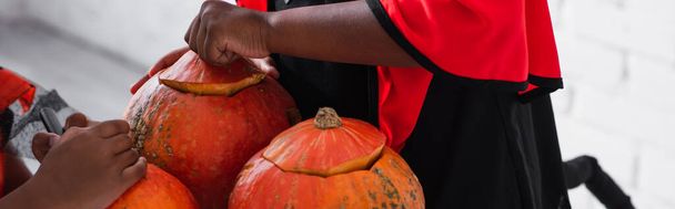 partial view of african american kids carving pumpkins, banner - Fotografie, Obrázek