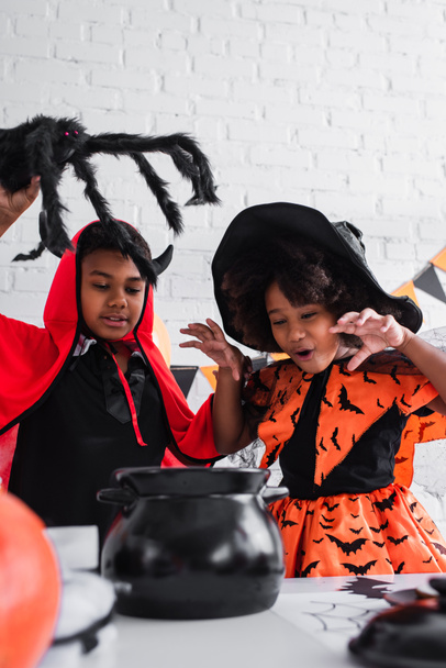 Afrikanische amerikanische Kinder in Halloween-Kostümen bereiten Trank im Hexenkessel zu - Foto, Bild