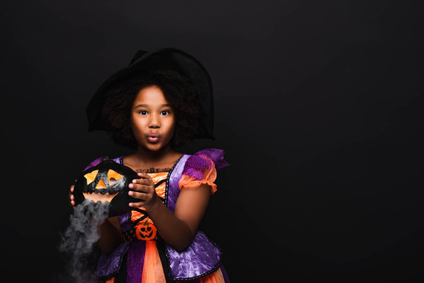 Afryki amerykanka dziewczyna w halloween kostium gospodarstwa rzeźbione dyni izolowane na czarny  - Zdjęcie, obraz