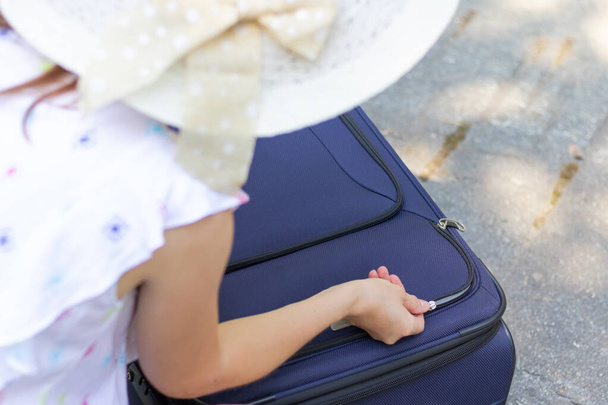 Женские руки открывают чемодан с вещами на лесной дороге в летний солнечный день. Крупный план. Селективный фокус - Фото, изображение