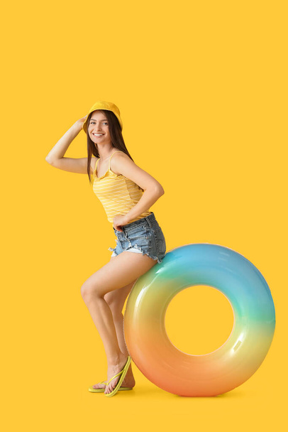 Young woman with inflatable ring on color background - 写真・画像