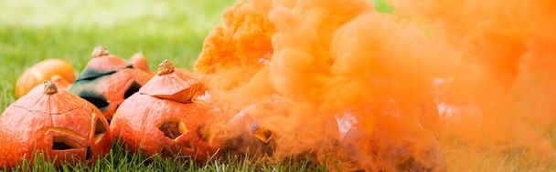humo naranja cerca de calabazas talladas en césped verde, pancarta - Foto, Imagen