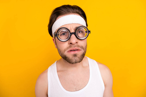 Portrait of attractive suspicious guy nerd sportsman looking at you spying isolated over bright yellow color background - Foto, Imagem