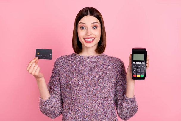Photo of cheerful lady presenting debit card terminal reader wear knitted pullover isolated pink color background - Photo, image