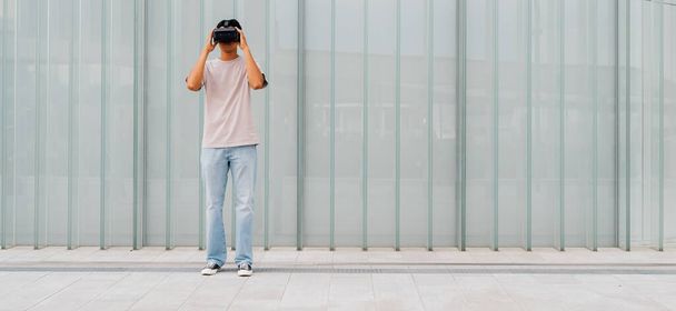 3Dゴーグルを使用して仮想現実を経験する若いアジアの男屋外-広告コピースペースバナー  - 写真・画像