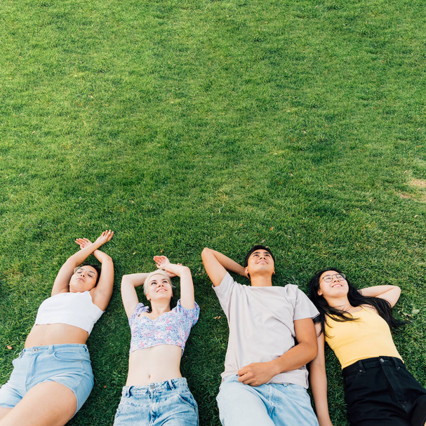 Group of young multiethnic friends outdoor lying grass smiling feeling free and relaxing - advertising copyspace banner - Fotografie, Obrázek