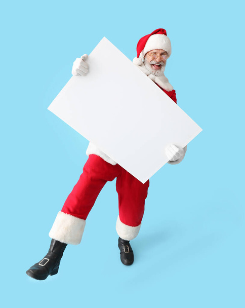 Happy Santa Claus with blank poster on color background - 写真・画像