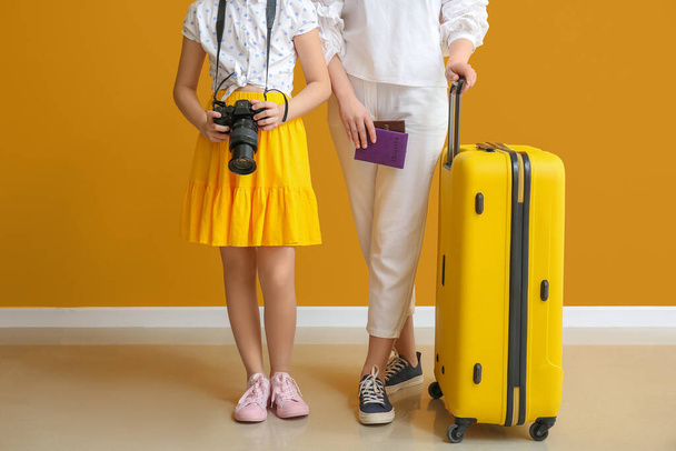 Happy mother and daughter with luggage near color wall. Concept of tourism - Foto, imagen