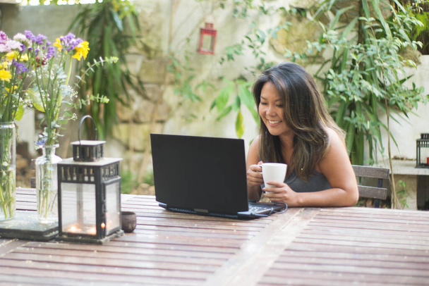 Portrait of attractive Japanese woman using laptop at backyard - Photo, Image