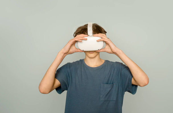 teen chlapec hraje virtuální realitu přes šedé pozadí, digitální technologie koncept, inovativní technologie - Fotografie, Obrázek
