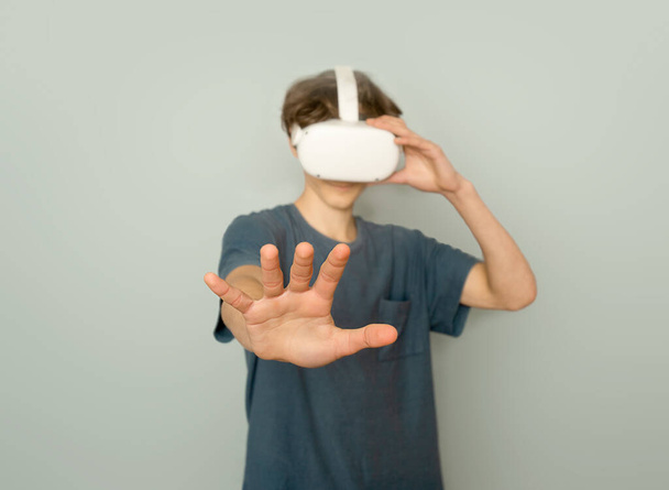 teen boy playing virtual reality over grey background, digital technology concept, innovative technologies - Photo, image