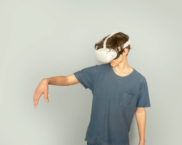 tiener jongen spelen virtual reality over grijze achtergrond, digitale technologie concept, innovatieve technologieën - Foto, afbeelding