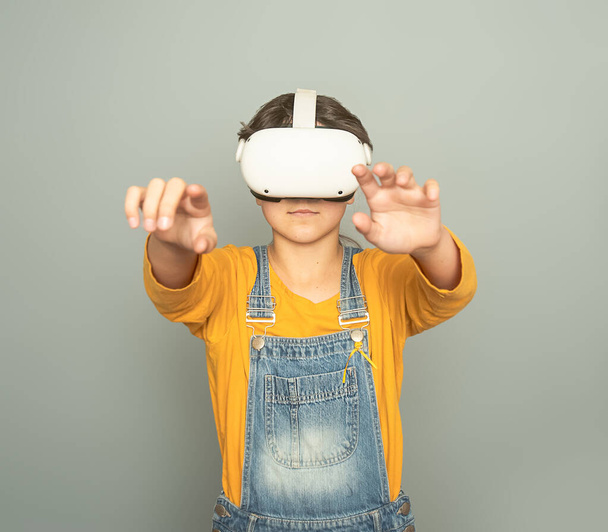 Девочка, играющая в виртуальную реальность на сером фоне, концепция цифровых технологий, инновационные технологии - Фото, изображение