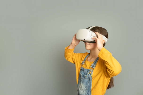 Gri arka plan, dijital teknoloji konsepti ve yenilikçi teknolojiler üzerinden sanal gerçeklik oynayan kız çocuğu - Fotoğraf, Görsel