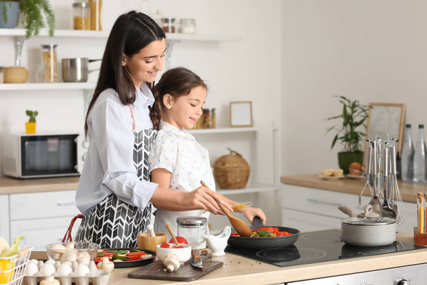 Junge Mutter und Tochter kochen gemeinsam in der heimischen Küche - Foto, Bild