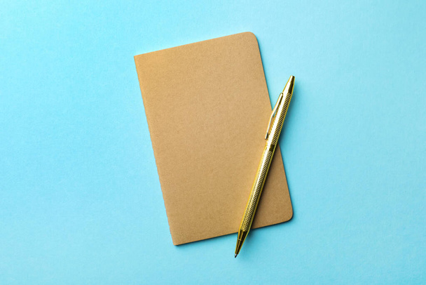 Stylish kraft planner with pen on light blue background, top view - 写真・画像