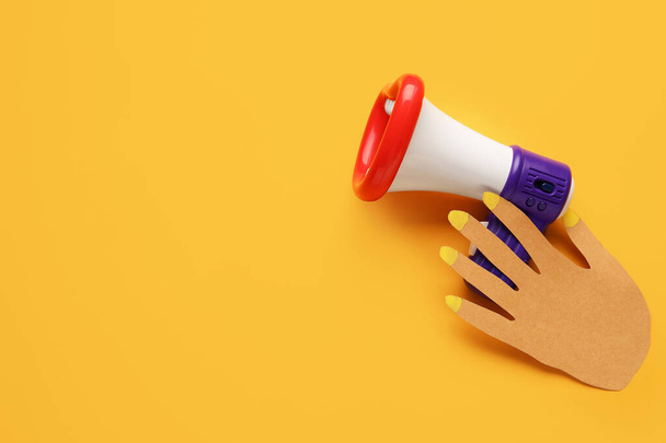 Мегафон с бумажной рукой на цветном фоне - Фото, изображение