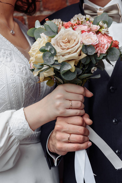 handen van jonge mensen met trouwringen. trouwdag details. calla bloemen. echtgenoten - Foto, afbeelding
