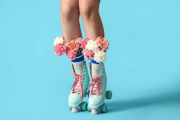 Pernas de mulher jovem em patins com flores no fundo de cor - Foto, Imagem