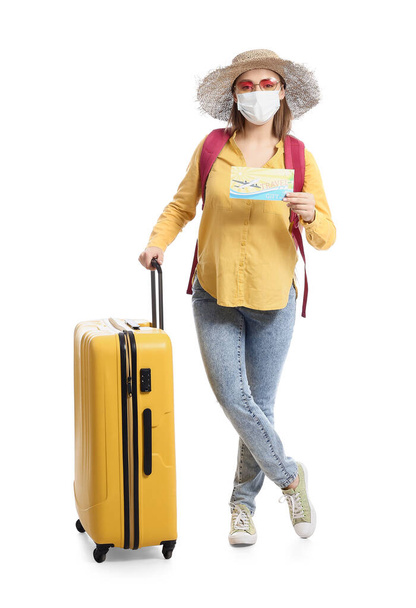 Vrouwelijke toerist in medisch masker op witte achtergrond - Foto, afbeelding