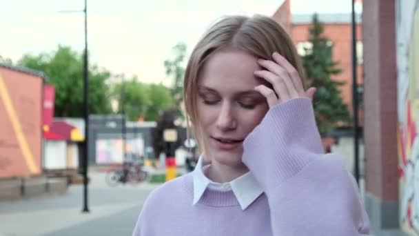Fiatal nő rövid szőke hajjal és vezeték nélküli fülhallgatóval - Felvétel, videó