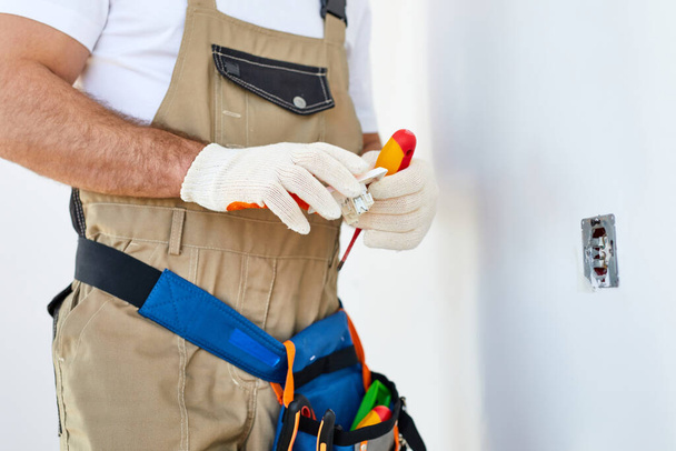Cropped caucasian man electrician holding screwdriver working on the plug electric - Фото, зображення