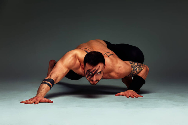 Animal instinct fitness instructor sportsman showing his incredible flexibility with an animal flow move in studio against a gray background - Photo, Image