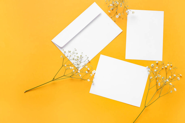 Envelop met blanco kaarten en bloemen op achtergrond - Foto, afbeelding