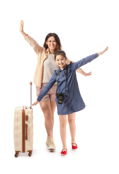 Happy mother and daughter with luggage on white background. Concept of tourism - Фото, изображение