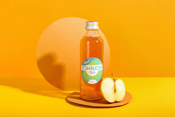 Fles lekkere kombucha thee met verse appel op kleur achtergrond - Foto, afbeelding