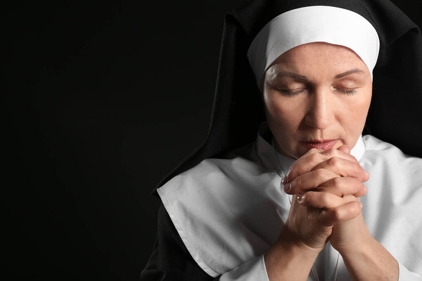 Зрелая монахиня молится на тёмном фоне - Фото, изображение