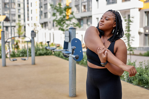 Beautiful african overweight young woman does fitness outdoors. Fat lady is training - Foto, Imagem