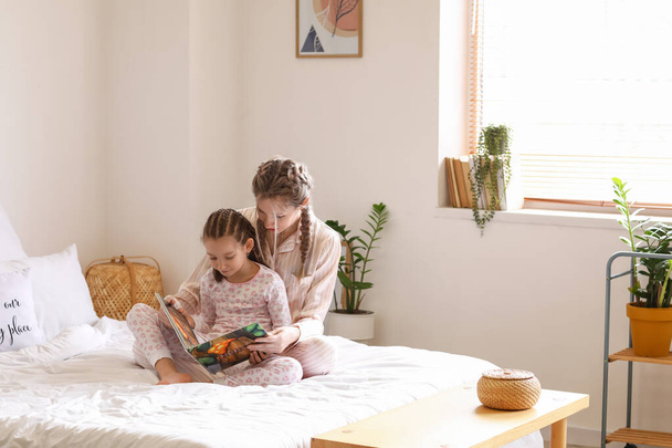 Little girl with her mother reading fairy-tale in bedroom - Foto, Imagen