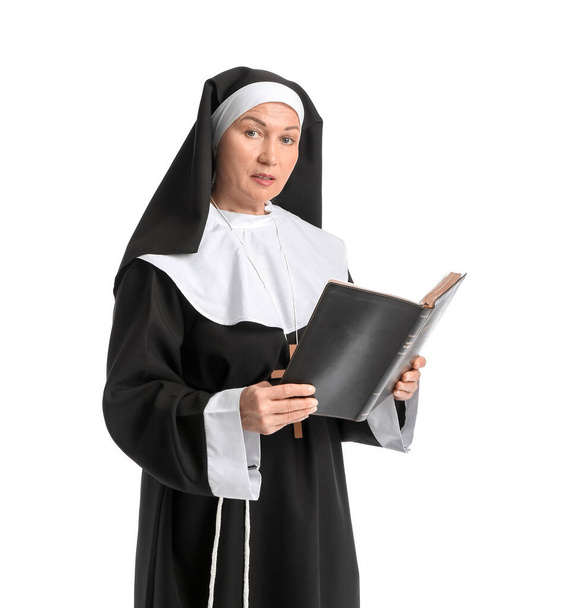 Dojrzała zakonnica czytająca Biblię na białym tle - Zdjęcie, obraz
