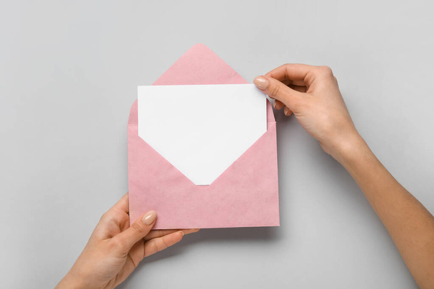 Female hands with envelope and blank card on light background - Zdjęcie, obraz