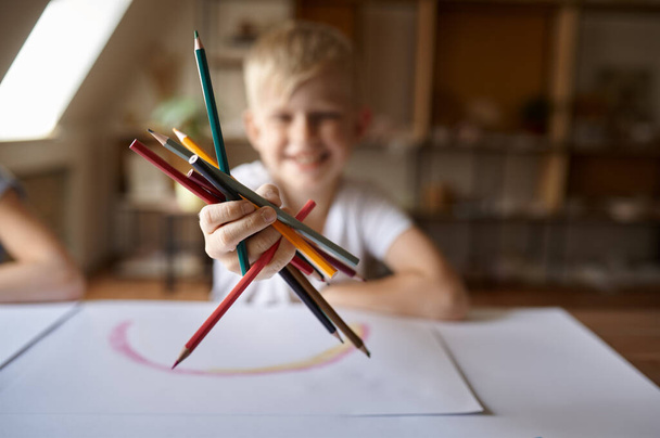 Маленький мальчик рисует карандашами, ребенок в мастерской - Фото, изображение