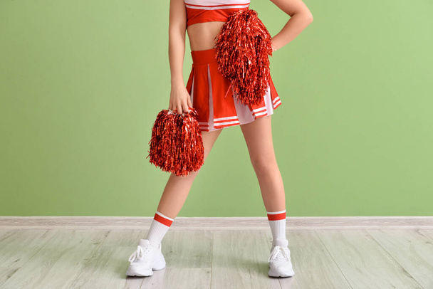 Beautiful cheerleader near color wall - Фото, изображение