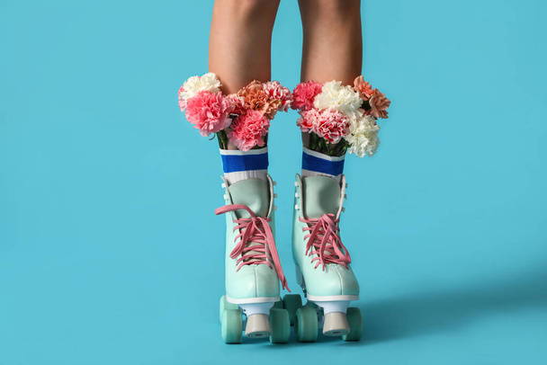 Renkli arka planda çiçekler olan patenli genç bir kadının bacakları. - Fotoğraf, Görsel