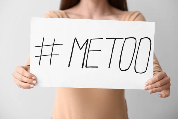 Young woman holding paper with hashtag MeToo on grey background - Foto, Imagem