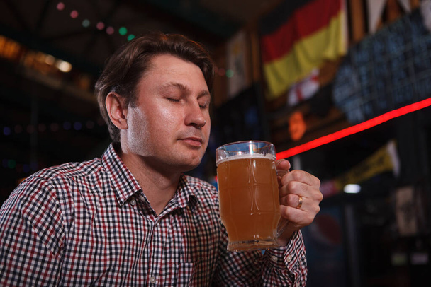 Close up de um homem maduro cheirando deliciosa cerveja artesanal em seu copo - Foto, Imagem