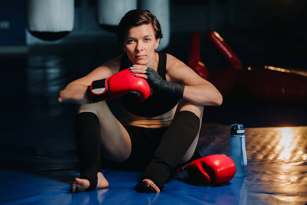 portrait of a female boxer in red gloves in the gym after training. - Fotografie, Obrázek