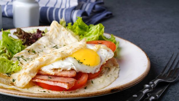 Omelette mit Spiegelei, Speck und Tomaten auf einem Teller.  - Foto, Bild