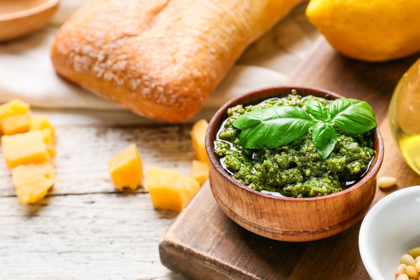 Bowl with tasty pesto sauce, bread and cheese on light wooden background, closeup - Fotoğraf, Görsel