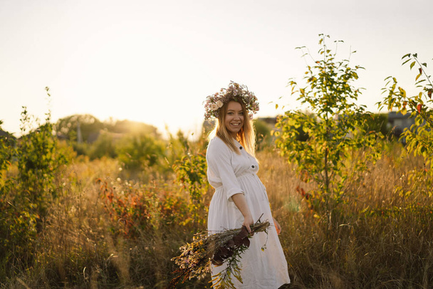 Ritratto di donna incinta. Una bella giovane donna incinta in un abito bianco cammina sul campo. - Foto, immagini