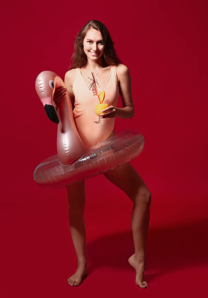Young woman with cocktail and inflatable ring on color background - Foto, Imagem