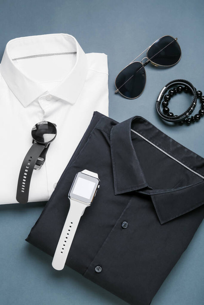 Male shirts, smartwatches and stylish accessories on color background - Foto, afbeelding