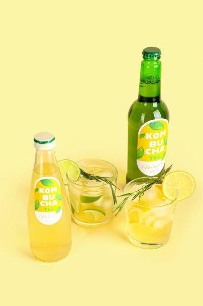 Flessen en glazen verse kombucha thee op kleur achtergrond - Foto, afbeelding