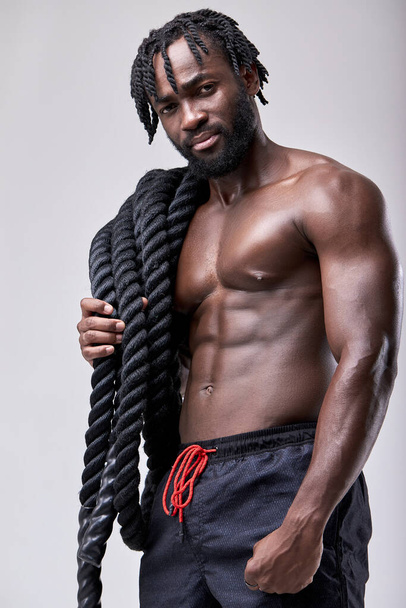 african-american bodybuilder working out with heavy ropes, posing at camera - Foto, Imagen