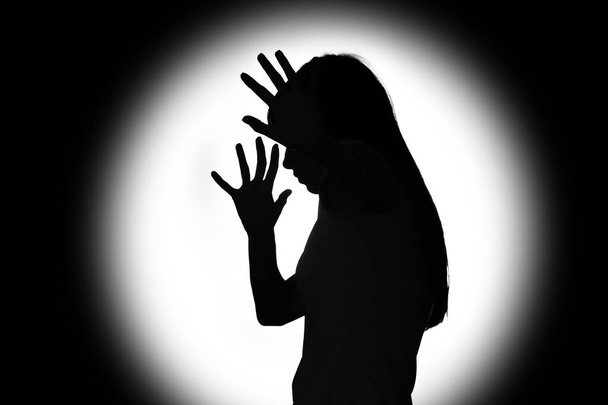 Silhouette of scared young woman on dark background. Concept of harassment - Fotoğraf, Görsel
