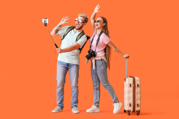 Couple of tourists taking selfie on color background - Photo, Image